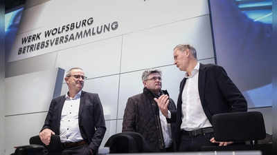 Konzernchef Oliver Blume (r.) berät sich vor seiner Rede mit VW-Verhandlungsführer Arne Meiswinke (Mitte). (Foto: Ronny Hartmann/POOL/dpa)