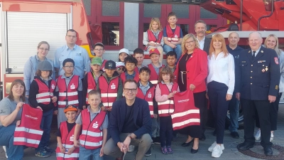 Mit Feuereifer bei der Feuerwehr: Die Neustädter Nachwuchskräfte stellten sich in ihren neuen knallroten Warnwesten zusammen mit ihren prominenten Gästen für ein gemeinsames Foto auf – den passenden Hintergrund inklusive.  (Foto: Sandra Buchwald)