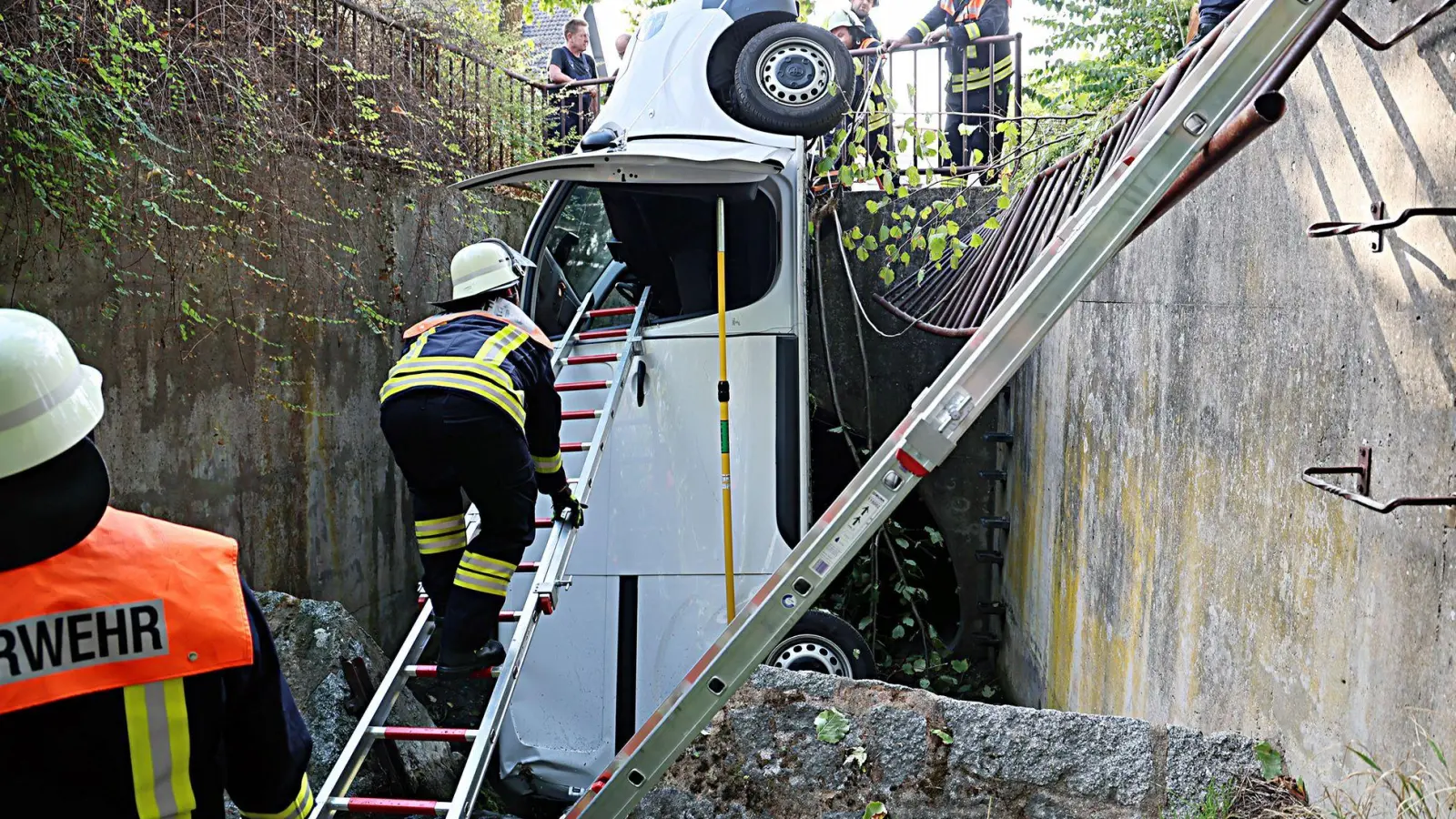 Ein Transporter durchbricht ein Metallgeländer und landet senkrecht im Bach.  (Foto: Ralf Hettler/dpa)