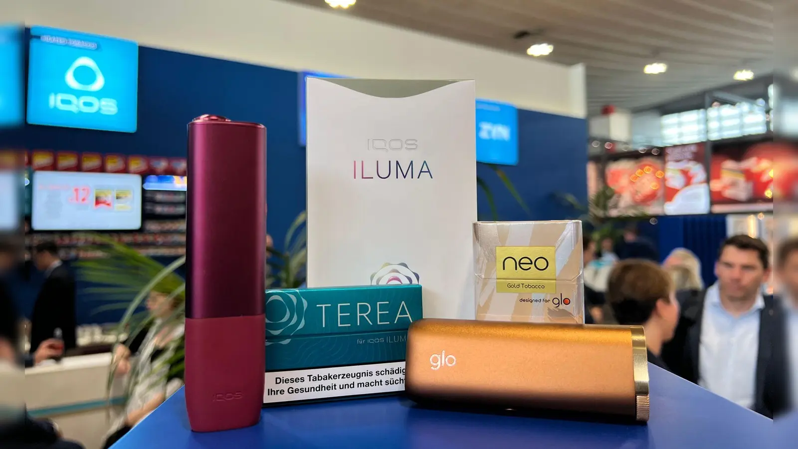 Ein Tabakerhitzer der Marke Iqos vom Hersteller Philip Morris und ein dazugehöriges Päckchen Tabaksticks der Marke Terea sowie das Konkurrenzprodukt Glo (mit Neo-Tabaksticks) des Herstellers BAT liegen bei der Fachmesse Intertabac in einer Messehalle. (Foto: Wolf von Dewitz/dpa)